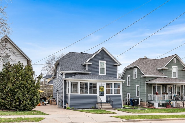 traditional home with covered porch, entry steps, cooling unit, and roof with shingles