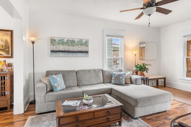 living area with baseboards, ceiling fan, and wood finished floors