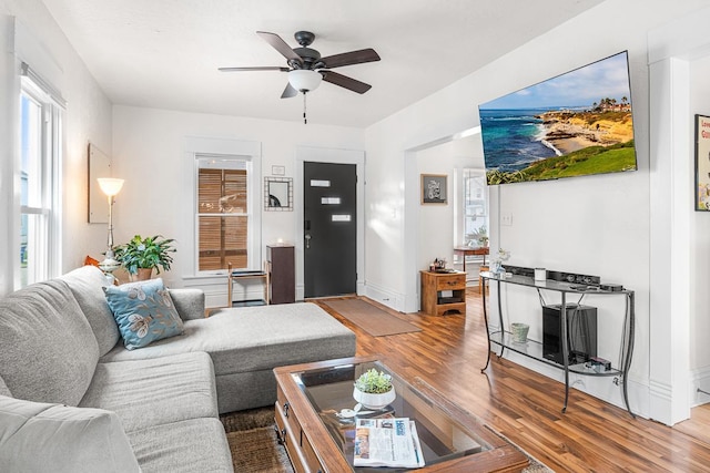 living area with baseboards, ceiling fan, and wood finished floors