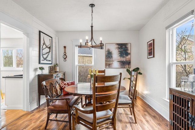 dining room with baseboards, an inviting chandelier, a healthy amount of sunlight, and light wood-style floors
