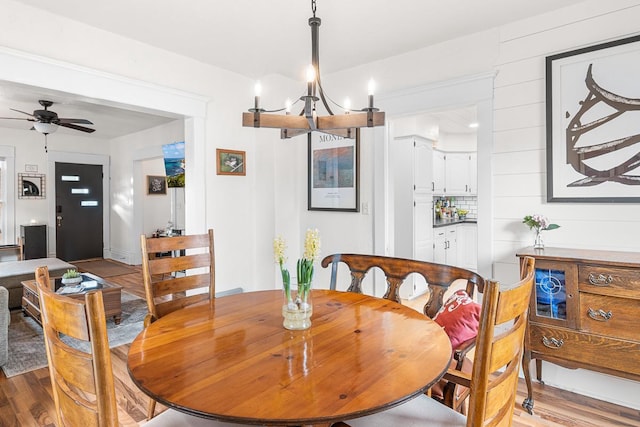 dining space featuring wood finished floors and ceiling fan with notable chandelier