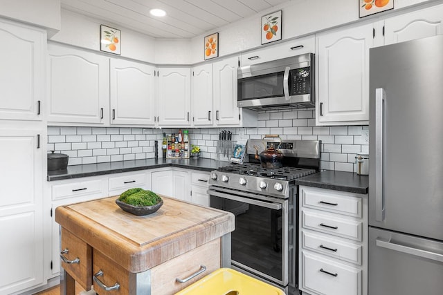 kitchen with white cabinets, stainless steel appliances, dark countertops, and tasteful backsplash