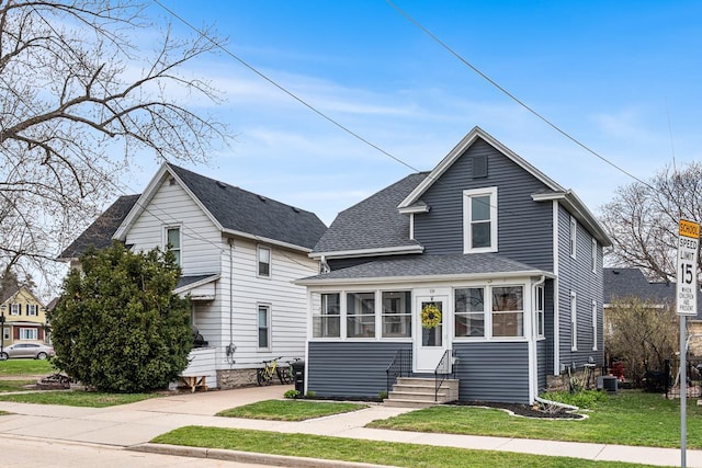 view of front of home featuring a front lawn, roof with shingles, central air condition unit, and entry steps