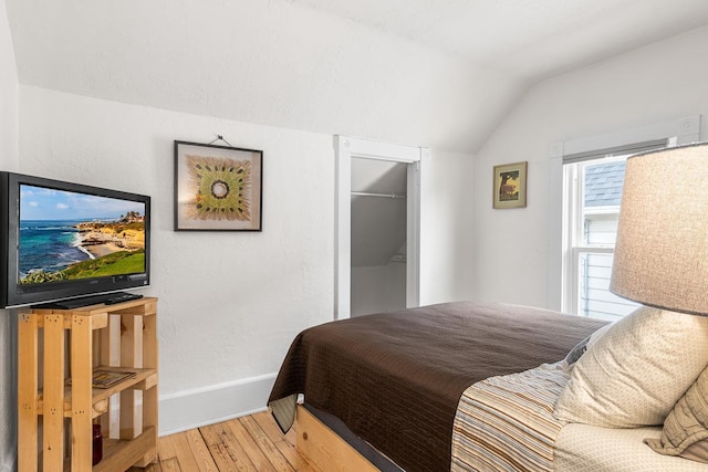 bedroom featuring baseboards, vaulted ceiling, and hardwood / wood-style flooring