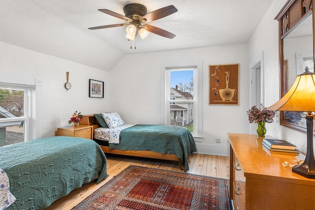 bedroom with a ceiling fan, multiple windows, lofted ceiling, and light wood-type flooring