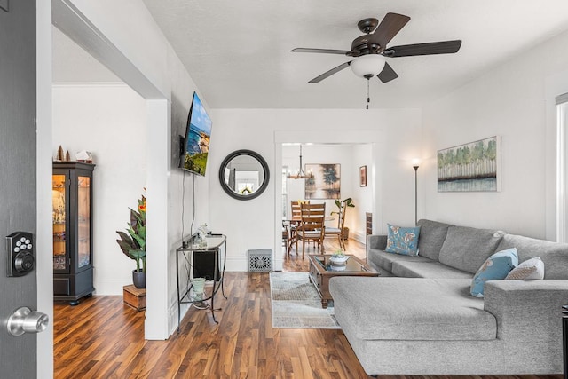 living room featuring baseboards, wood finished floors, and ceiling fan with notable chandelier