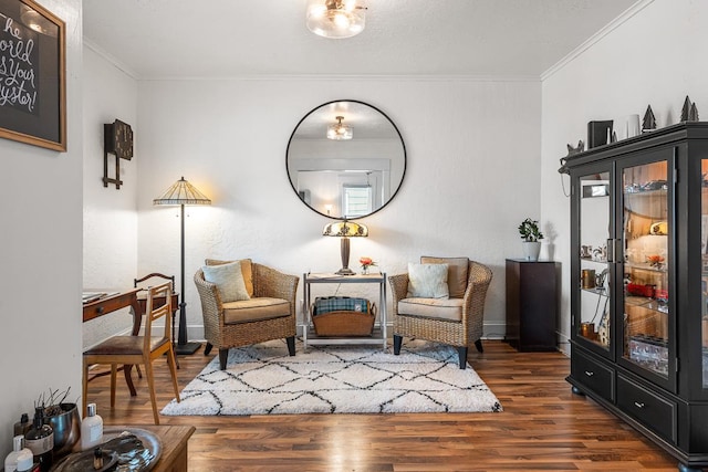 sitting room with baseboards, ornamental molding, and wood finished floors