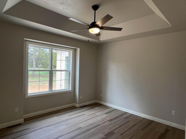 empty room featuring baseboards, wood finished floors, and a ceiling fan