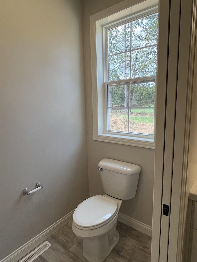 bathroom featuring wood finished floors, toilet, visible vents, and baseboards