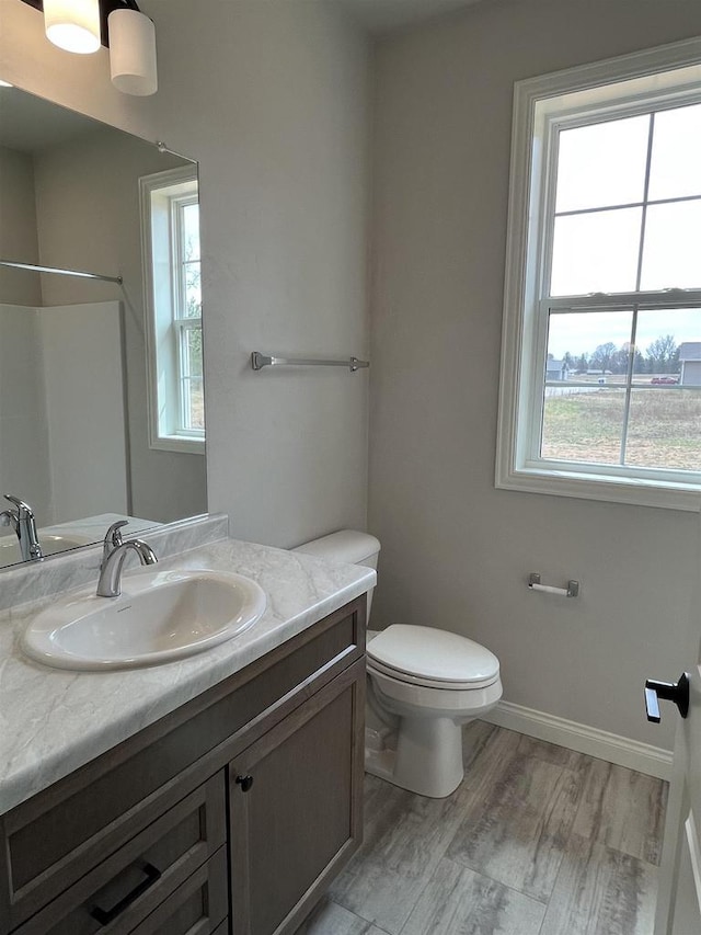 bathroom with wood finished floors, toilet, vanity, and plenty of natural light