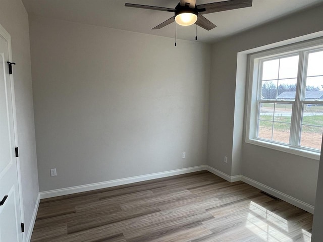 spare room featuring baseboards, wood finished floors, and a ceiling fan