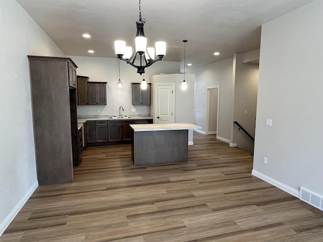 kitchen featuring a sink, a notable chandelier, a center island, visible vents, and light countertops