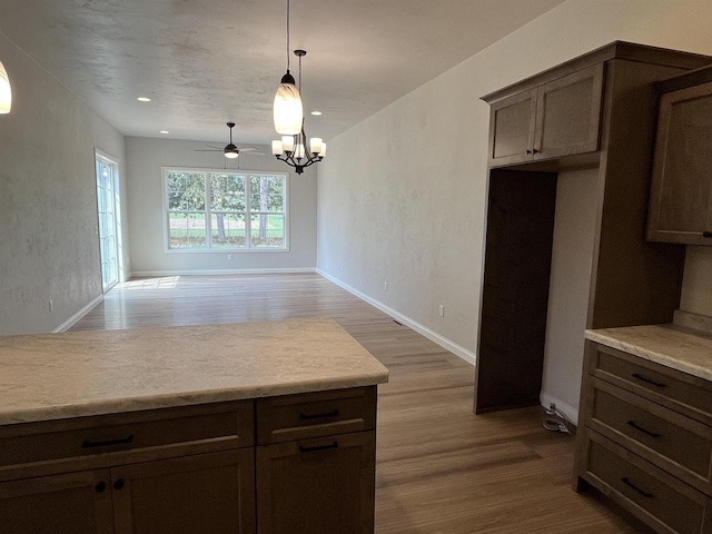 kitchen featuring wood finished floors, a notable chandelier, decorative light fixtures, and light countertops