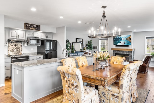 dining space with recessed lighting, a glass covered fireplace, a chandelier, and light wood-type flooring