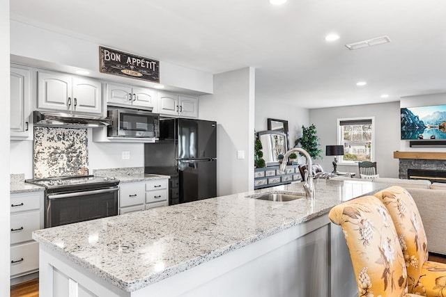 kitchen with a sink, visible vents, stainless steel appliances, open floor plan, and extractor fan