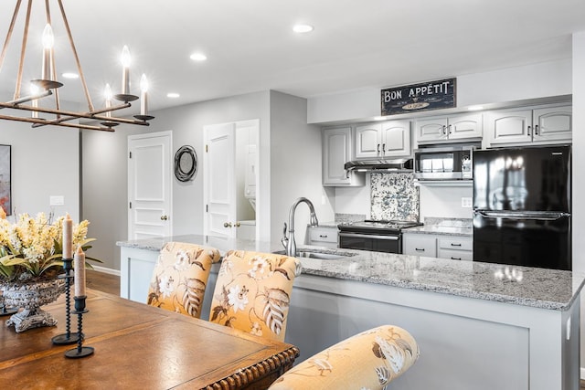 kitchen featuring recessed lighting, exhaust hood, a sink, stainless steel appliances, and a notable chandelier