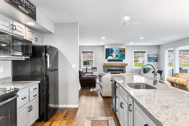 kitchen featuring black appliances, open floor plan, plenty of natural light, and a sink