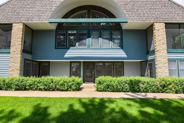 exterior space with roof with shingles and a front yard