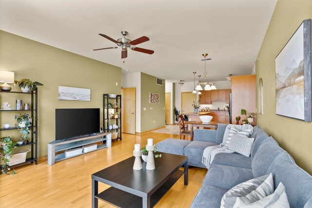living area with visible vents, a ceiling fan, and light wood-style flooring