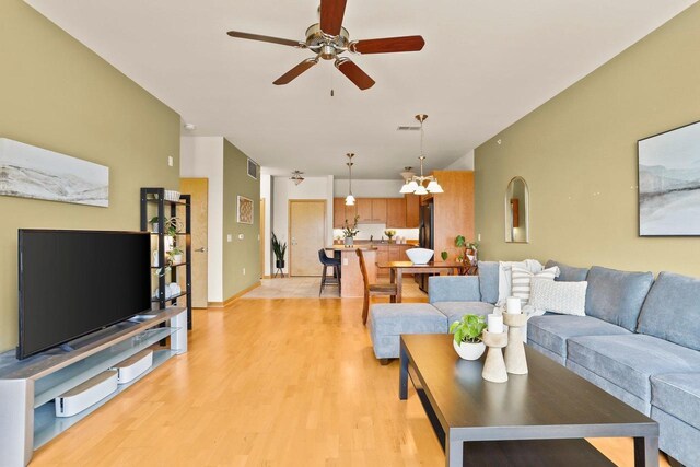 living room featuring light wood-style floors, ceiling fan, and visible vents
