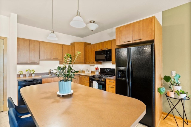 kitchen featuring a kitchen bar, pendant lighting, a center island, a sink, and black appliances