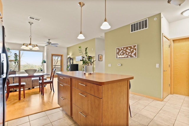 kitchen with ceiling fan, light tile patterned floors, a kitchen island, visible vents, and pendant lighting