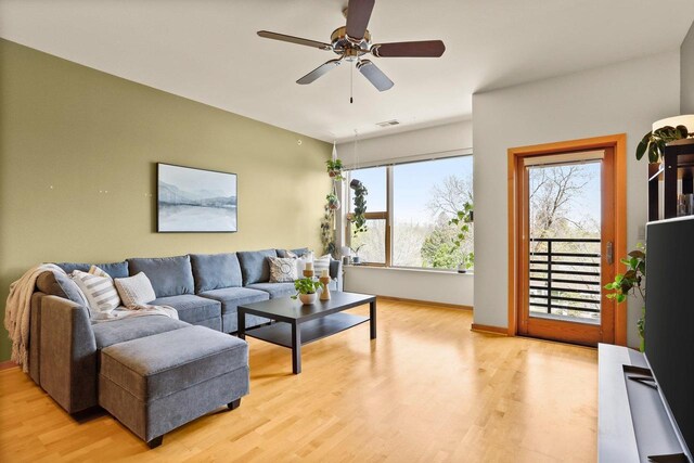 living room with a ceiling fan, visible vents, and light wood-type flooring