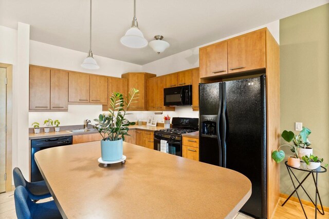 kitchen featuring a kitchen bar, pendant lighting, a center island, a sink, and black appliances