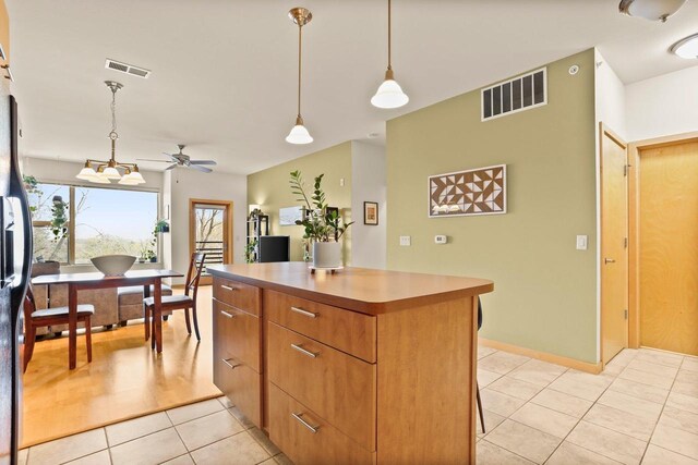 kitchen with ceiling fan, light tile patterned floors, a kitchen island, visible vents, and pendant lighting