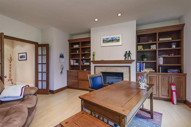 home office with light wood finished floors, french doors, baseboards, and a glass covered fireplace