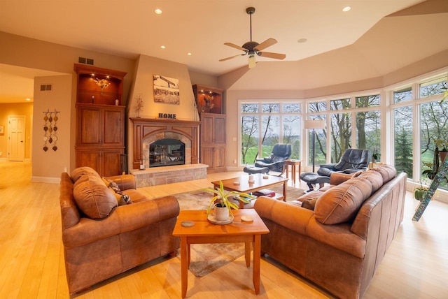 living area with a wealth of natural light, visible vents, light wood-style flooring, and a ceiling fan