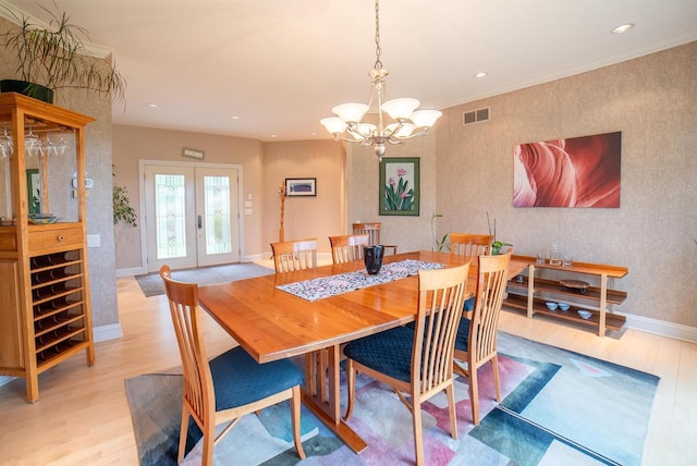 dining room with visible vents, a chandelier, light wood finished floors, baseboards, and wallpapered walls