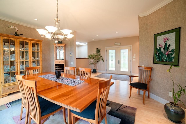 dining room with a notable chandelier, french doors, baseboards, crown molding, and wood finished floors