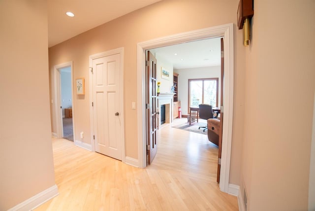 hall with baseboards, light wood-style flooring, and recessed lighting