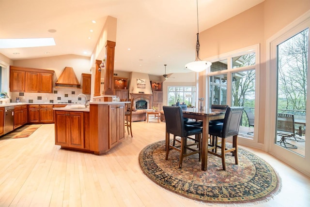 dining room with light wood-style floors, vaulted ceiling with skylight, and a glass covered fireplace