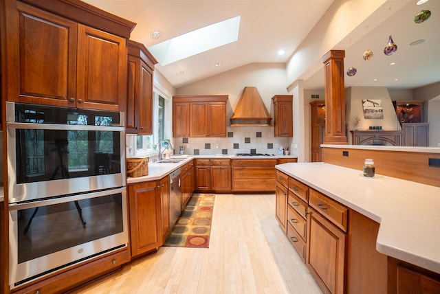 kitchen with light wood-style flooring, a sink, light countertops, appliances with stainless steel finishes, and decorative backsplash