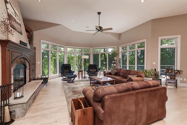 living room featuring light wood-style floors, a glass covered fireplace, ceiling fan, and plenty of natural light