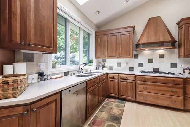 kitchen featuring a sink, stainless steel dishwasher, custom exhaust hood, and plenty of natural light
