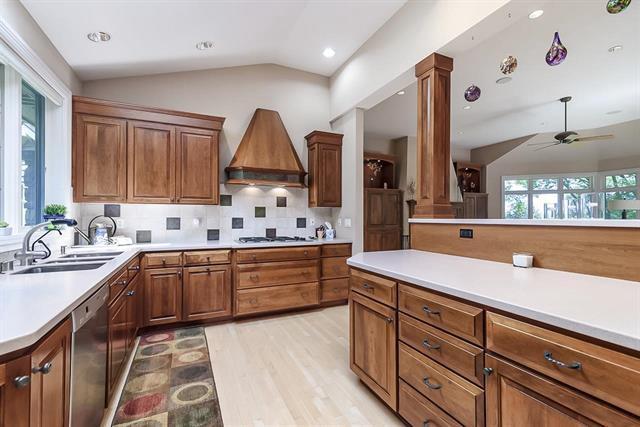 kitchen with lofted ceiling, dishwasher, custom exhaust hood, a sink, and decorative columns