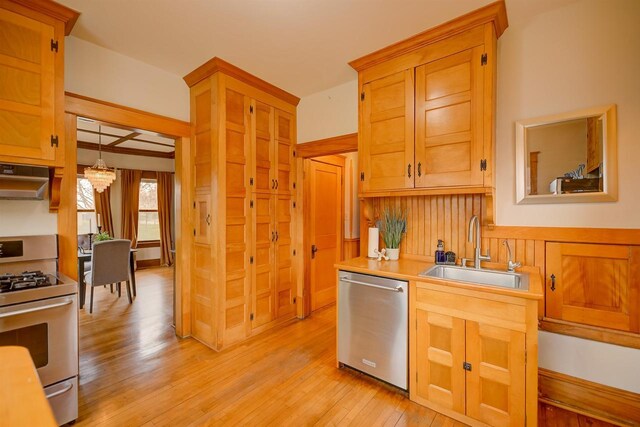 1324 Washington Ave, Oshkosh, WI 54901 - kitchen with a notable chandelier, a sink, light wood-style flooring, stainless steel appliances, and under cabinet range hood