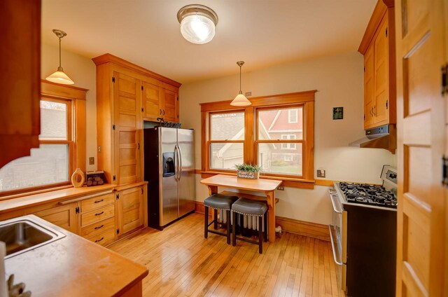 1324 Washington Ave, Oshkosh, WI 54901 - kitchen with extractor fan, light wood-type flooring, light countertops, hanging light fixtures, and stainless steel appliances