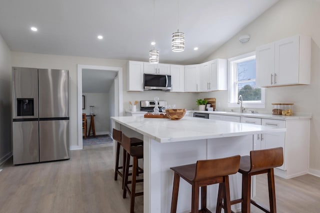 3326 6 Mile Rd, Racine, WI 53402 - kitchen featuring appliances with stainless steel finishes, a breakfast bar area, light stone counters, and light wood-style flooring