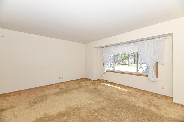 spare room featuring visible vents, carpet, and baseboards