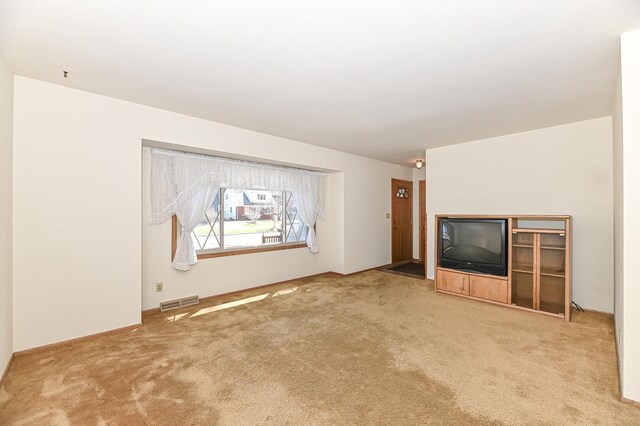 unfurnished living room with visible vents and carpet flooring