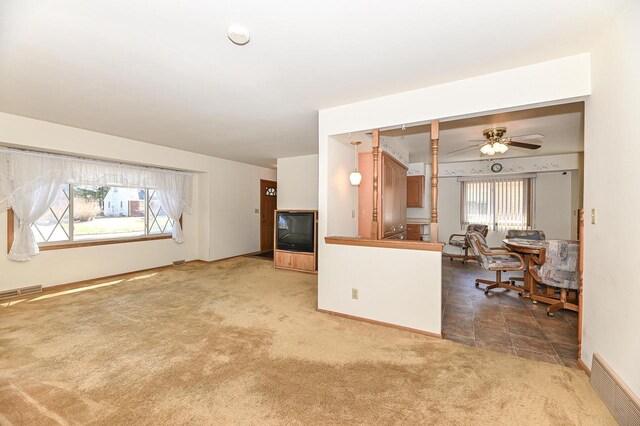living room featuring baseboards, carpet flooring, ceiling fan, and visible vents