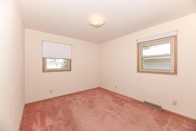 unfurnished room with light colored carpet, visible vents, and baseboards