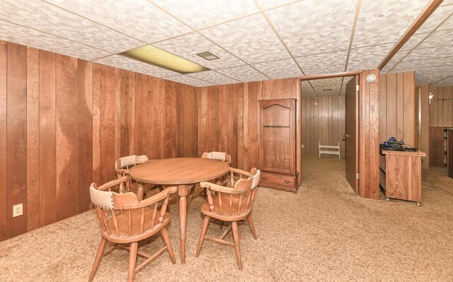dining room featuring wooden walls and carpet flooring
