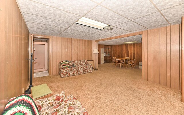 living area featuring visible vents, wood walls, and carpet