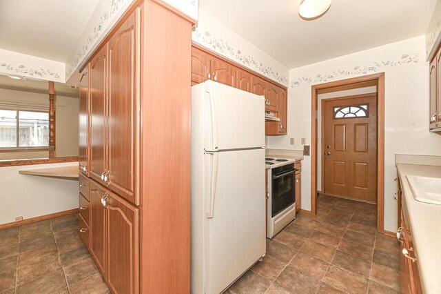 kitchen featuring light countertops, a sink, baseboards, and white appliances