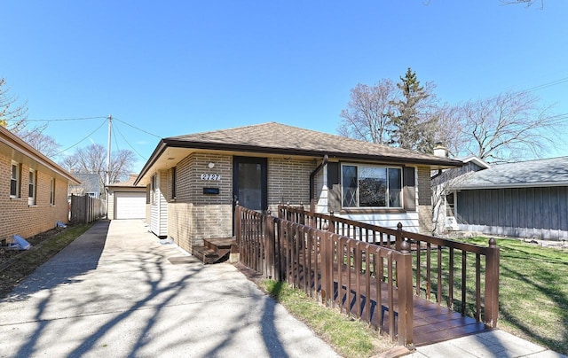 bungalow featuring an outdoor structure, roof with shingles, a detached garage, and brick siding